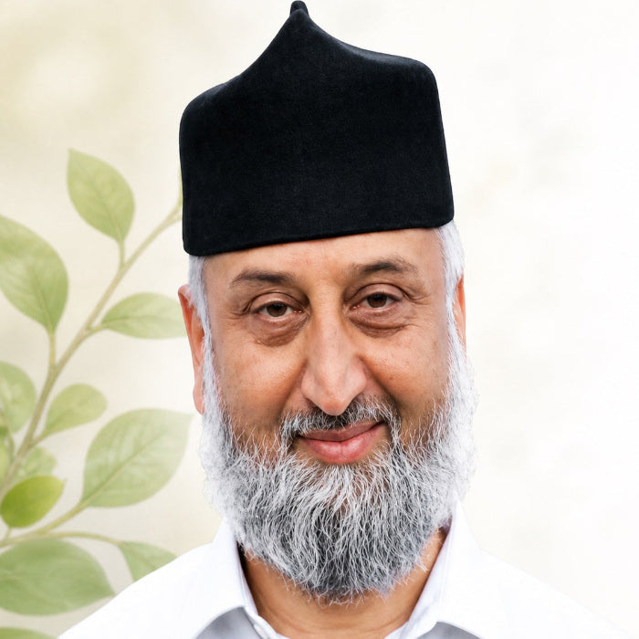 Man wearing a black turban with a light green leafy background